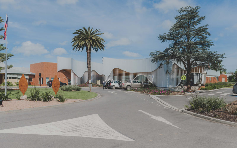 Photo of the front entry to Yarram Medical Centre with two tall trees and the medical centre in the background
