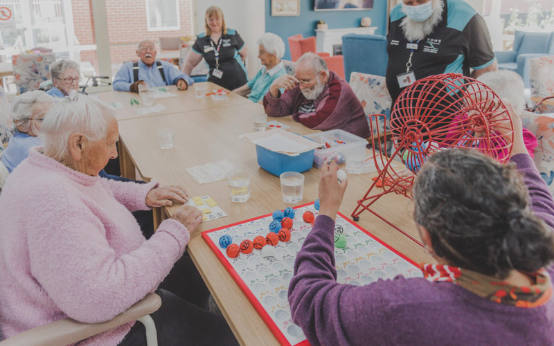 Photo of residents at a nursing home sitting at a table playing bingo