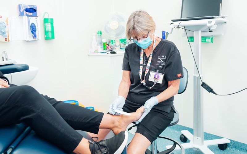 Photo of a female nurse in medical treatment room providing foot care to a patient